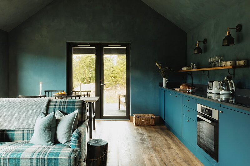 salon bleu avec cuisine ouverte maison en bois Glen Glack domaine Atholl en Ecosse salon bleu avec cuisine ouverte maison en bois Glen Glack domaine Atholl en Ecosse