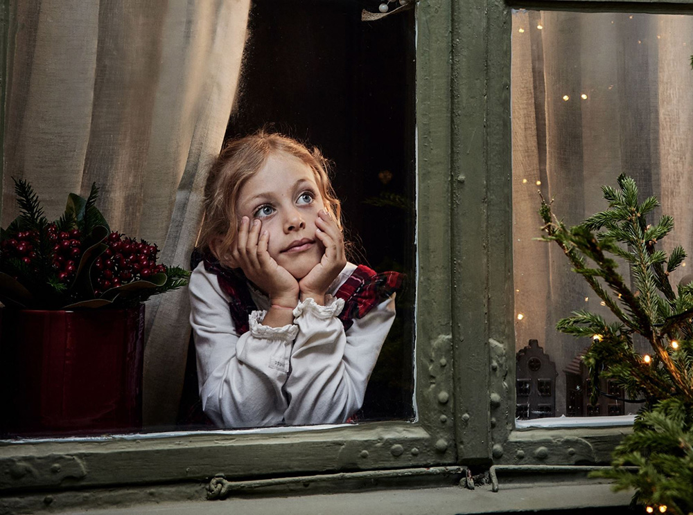 enfant regardant par la fenêtre maison avec décoration Noël traditionnel