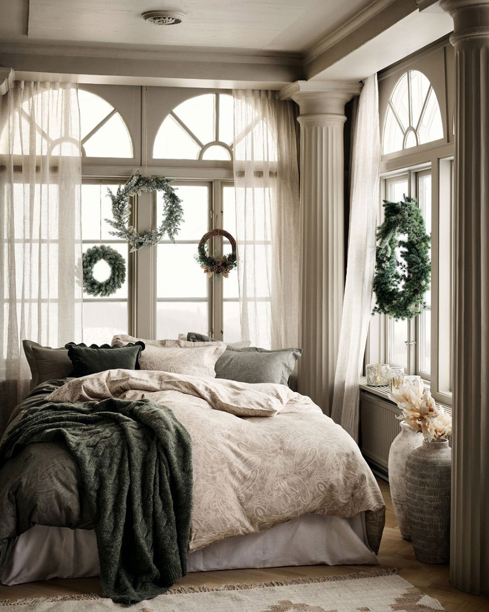 chambre beige et verte avec couronnes sapin sur fenêtres