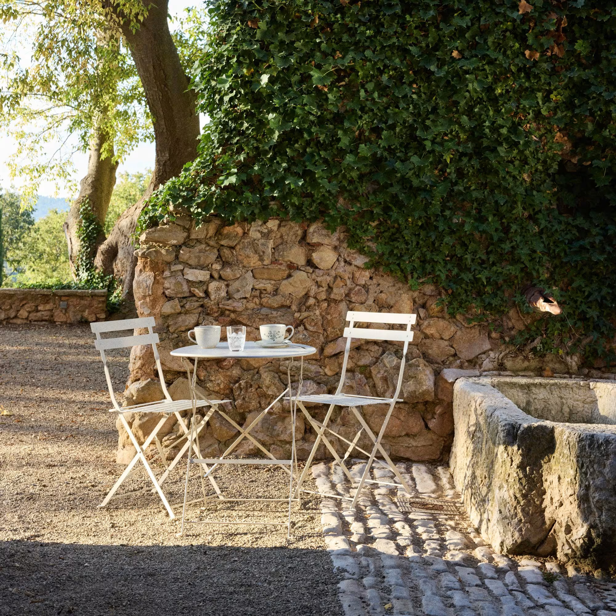 salon de jardin Maisons du Monde collection French Riviera dans jardin avec mur de pierres salon de jardin Maisons du Monde collection French Riviera dans jardin avec mur de pierres