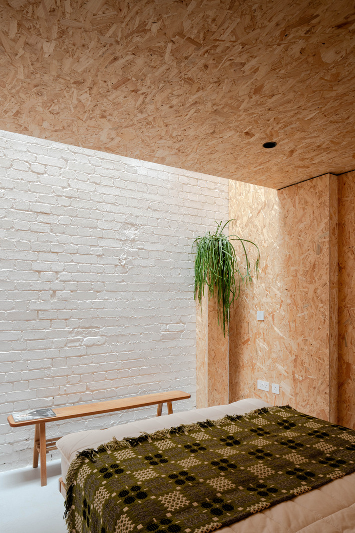 chambre semi-ouverte murs et plafond OSB et briques blanches