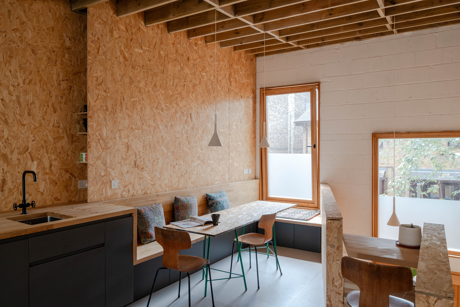 salle à manger et cuisine ouverte grise design murs OSB petite maison 51m2