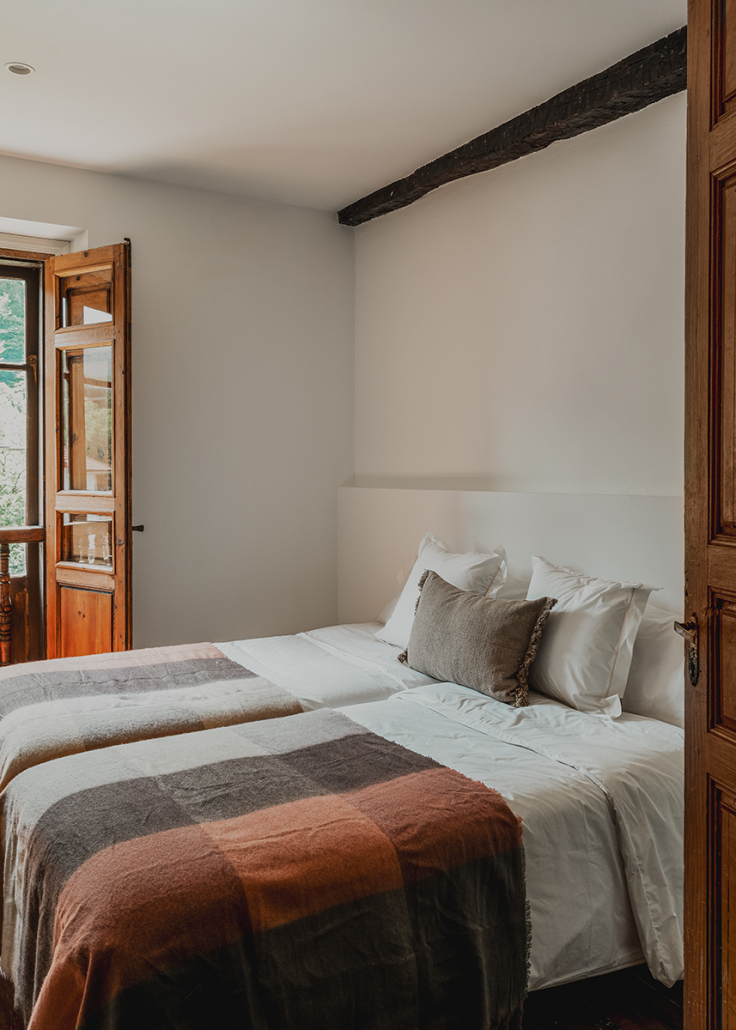 chambre avec poutres et murs pierres maison de village rénovée Espagne