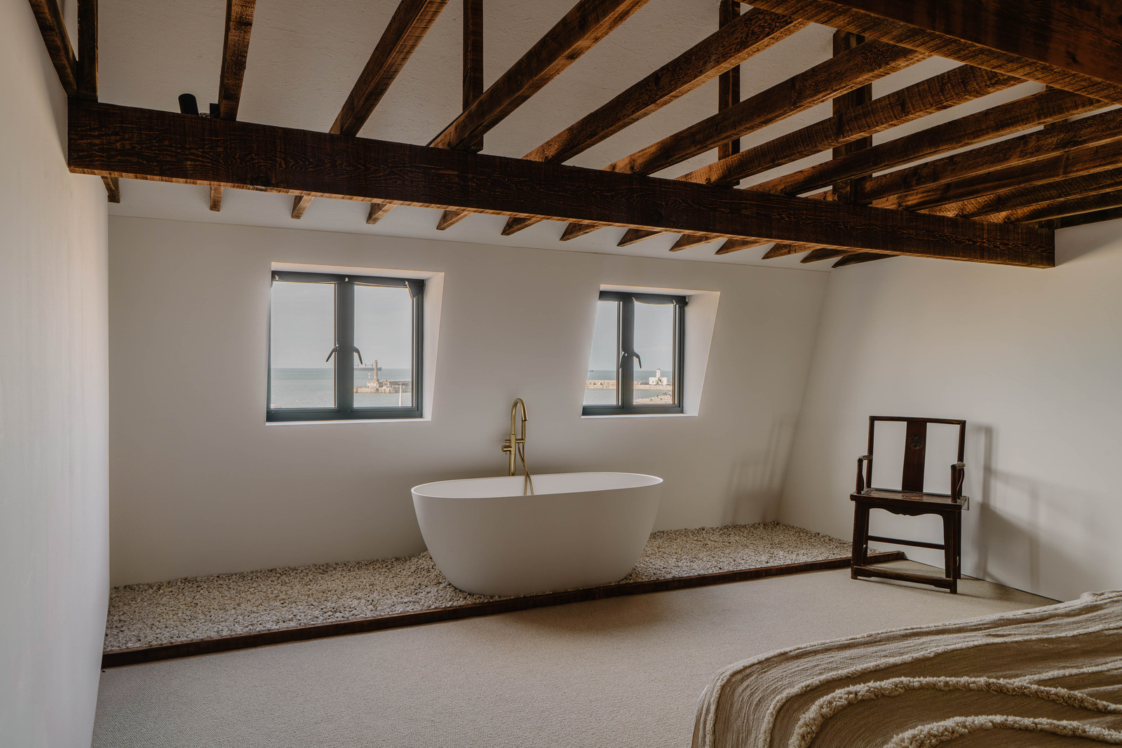 baignoire îlot design dans chambre avec poutres et mur de pierres décoration naturelle baignoire îlot design dans chambre avec poutres et mur de pierres décoration naturelle