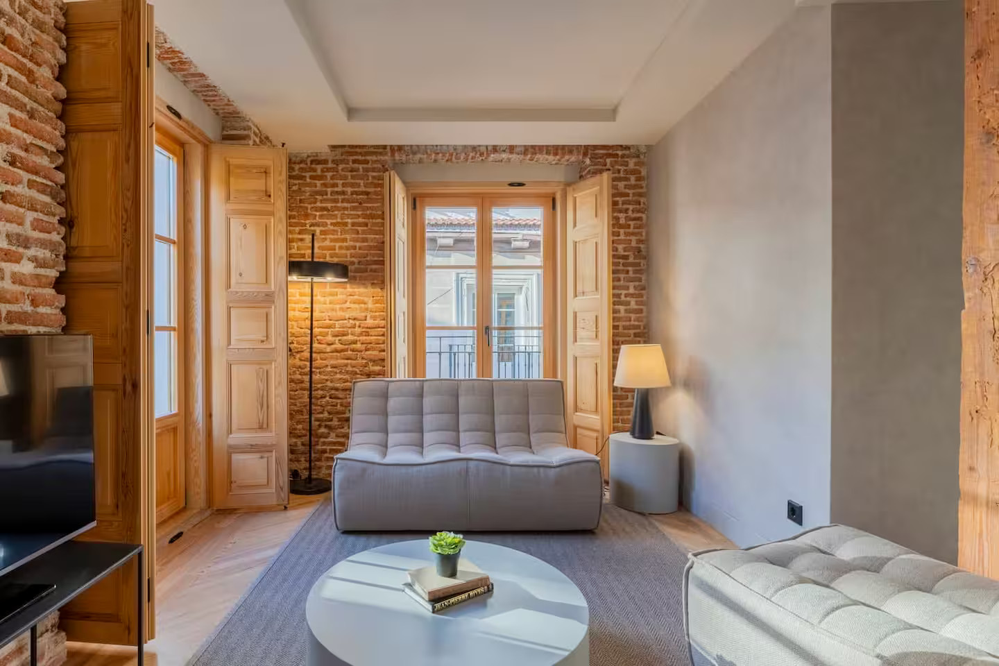 salon studio optimisé en deux-pièces avec murs briques et volets intérieurs