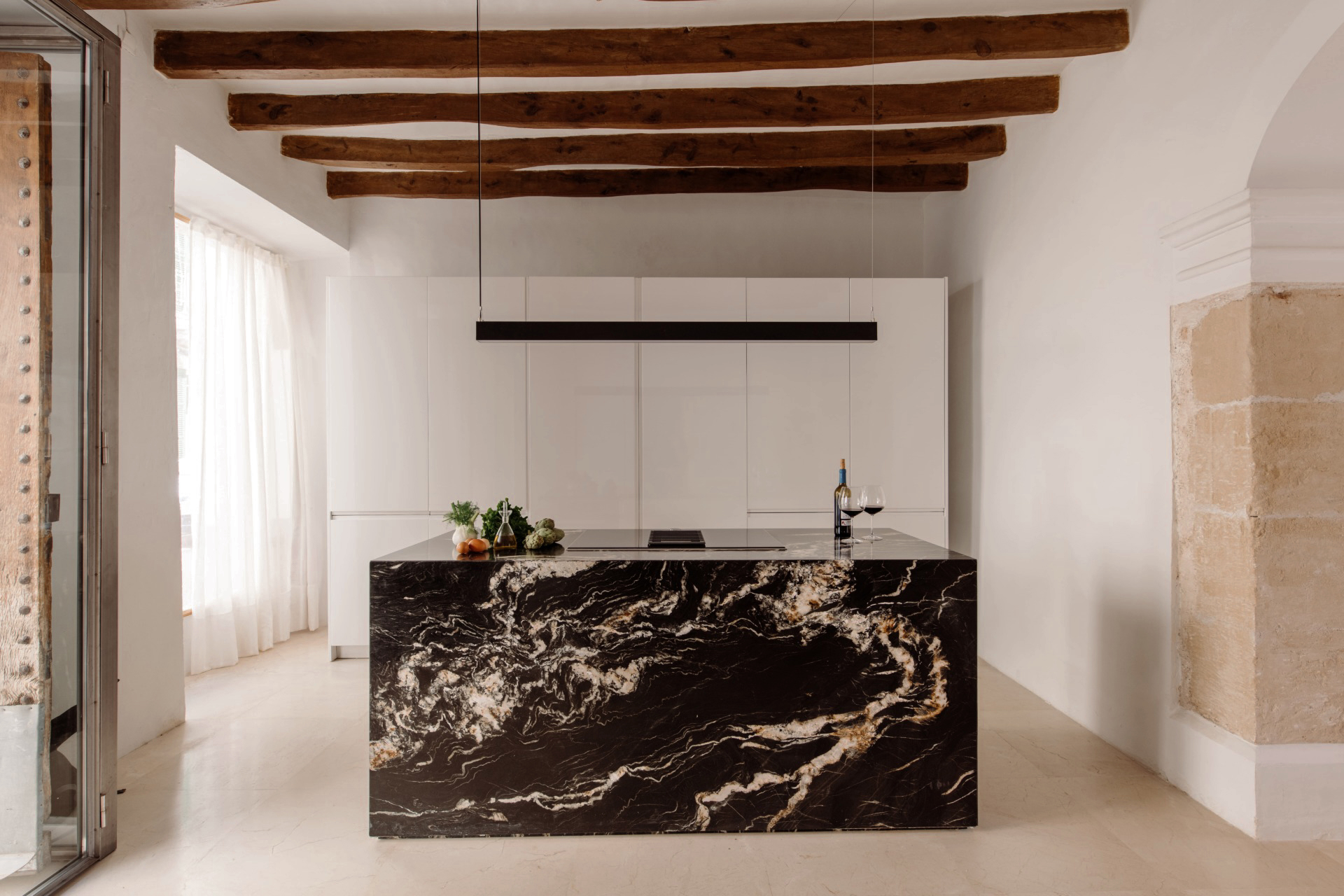 cuisine design blanche avec îlot marbre noir avec poutres décoration contemporaine maison ancienne Majorque cuisine design blanche avec îlot marbre noir avec poutres décoration contemporaine maison ancienne Majorque