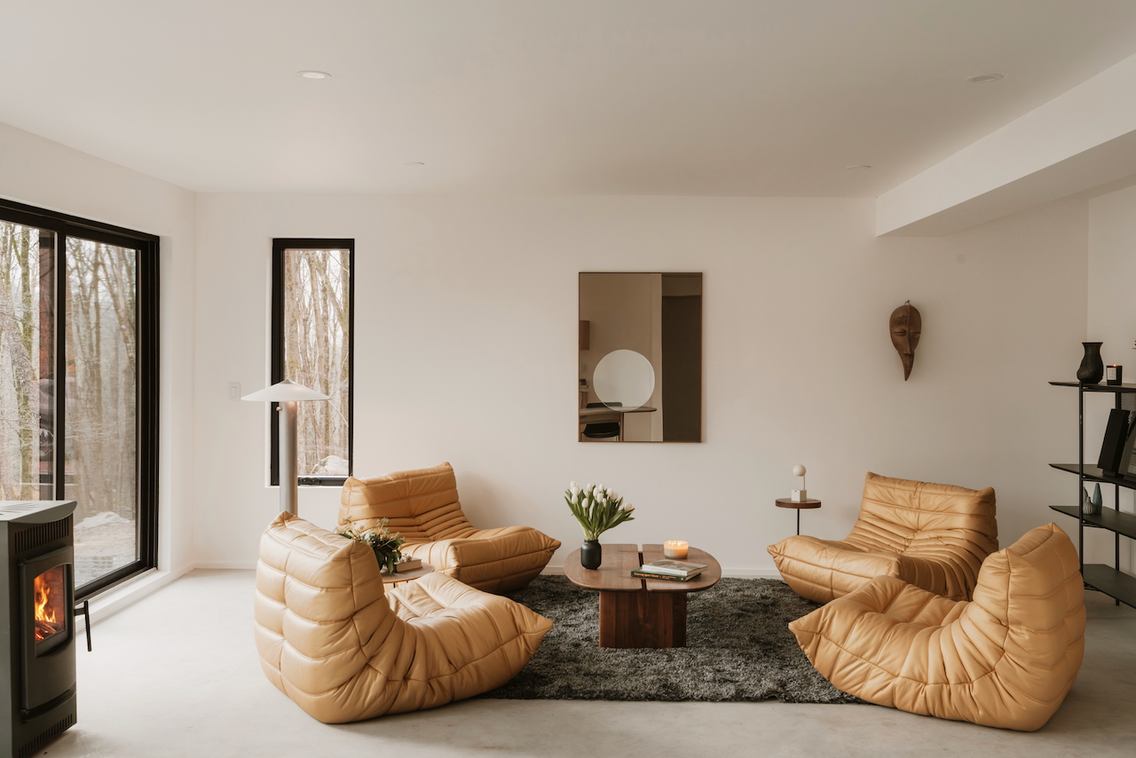 salon design avec baies vitrées et fauteuil Togo et poêle maison hors réseau conçue par un architecte salon design avec baies vitrées et fauteuil Togo et poêle maison hors réseau conçue par un architecte