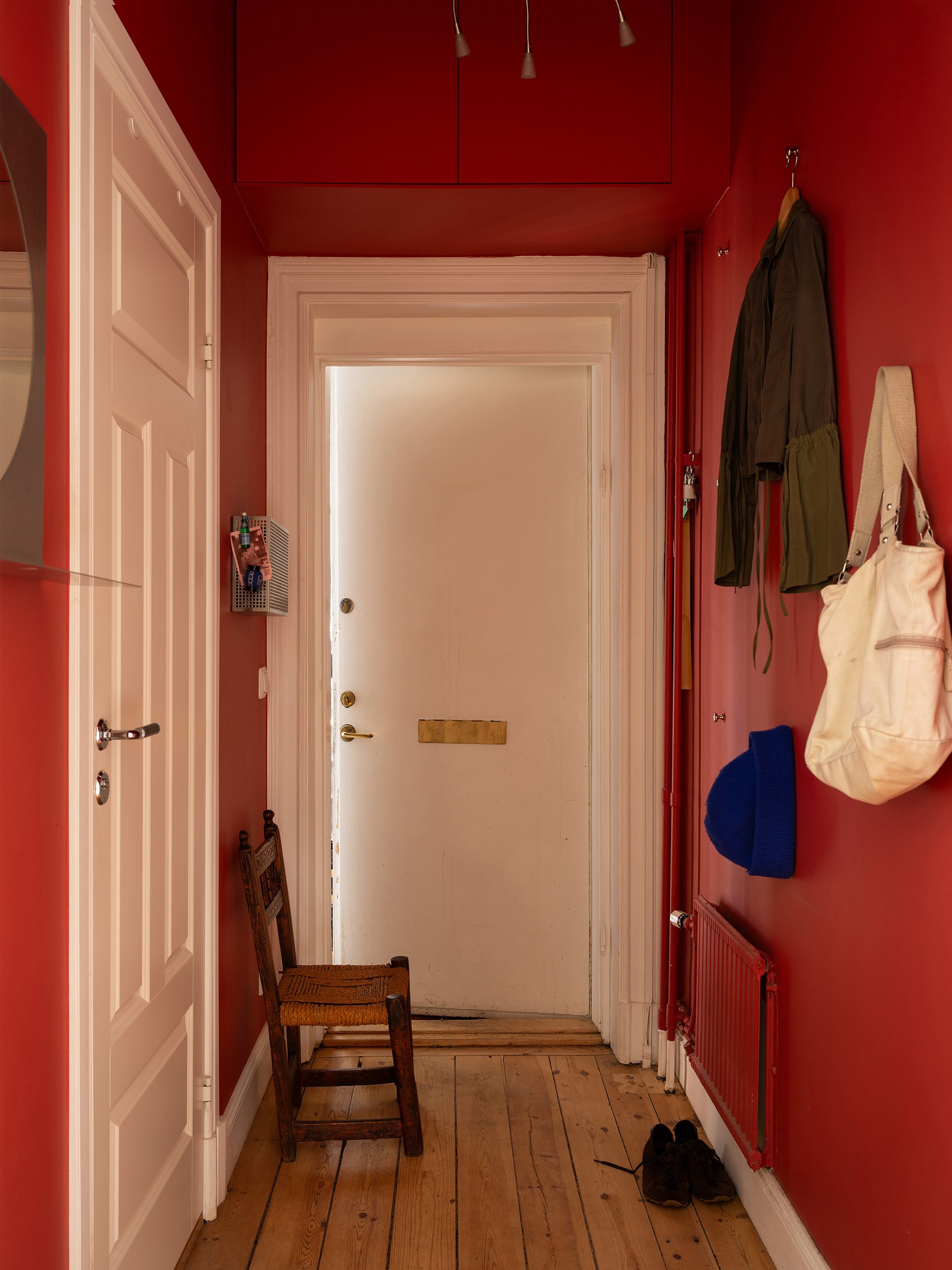 entrée murs rouges décoration scandinave appartement deux-pièces 48m2 style vintage dans immeuble du 19e siècle entrée murs rouges décoration scandinave appartement deux-pièces 48m2 style vintage dans immeuble du 19e siècle