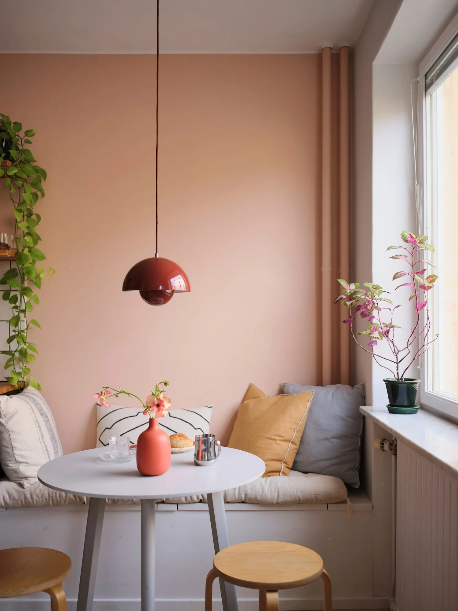 Pink wall kitchen with dining area and bench, colourful 54m2 Scandinavian-style flat