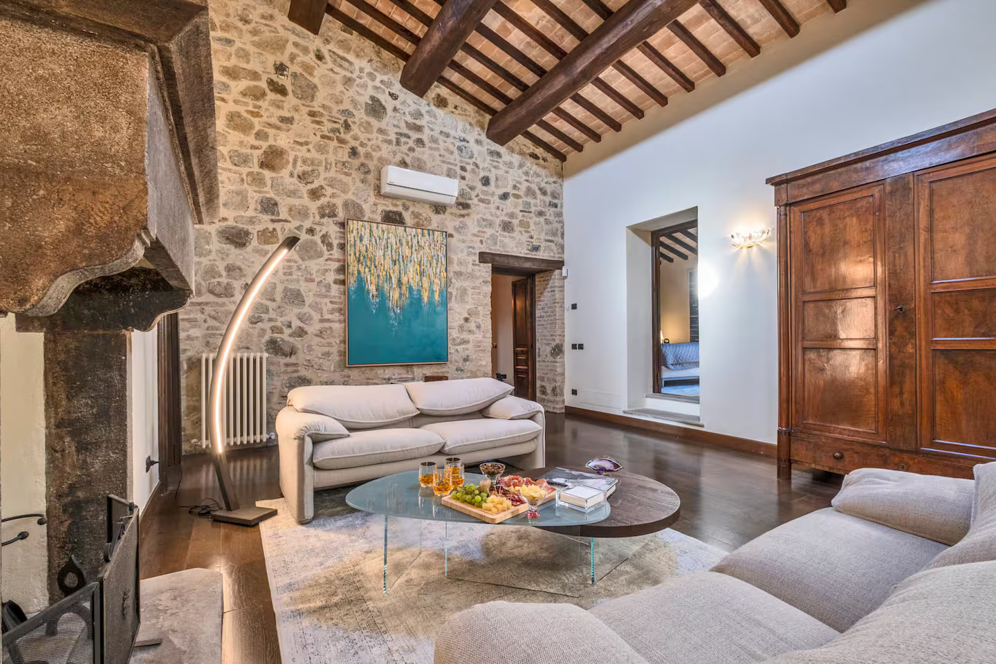 salon avec poutres cheminée et mur pierres maison en pierres Toscane Italie