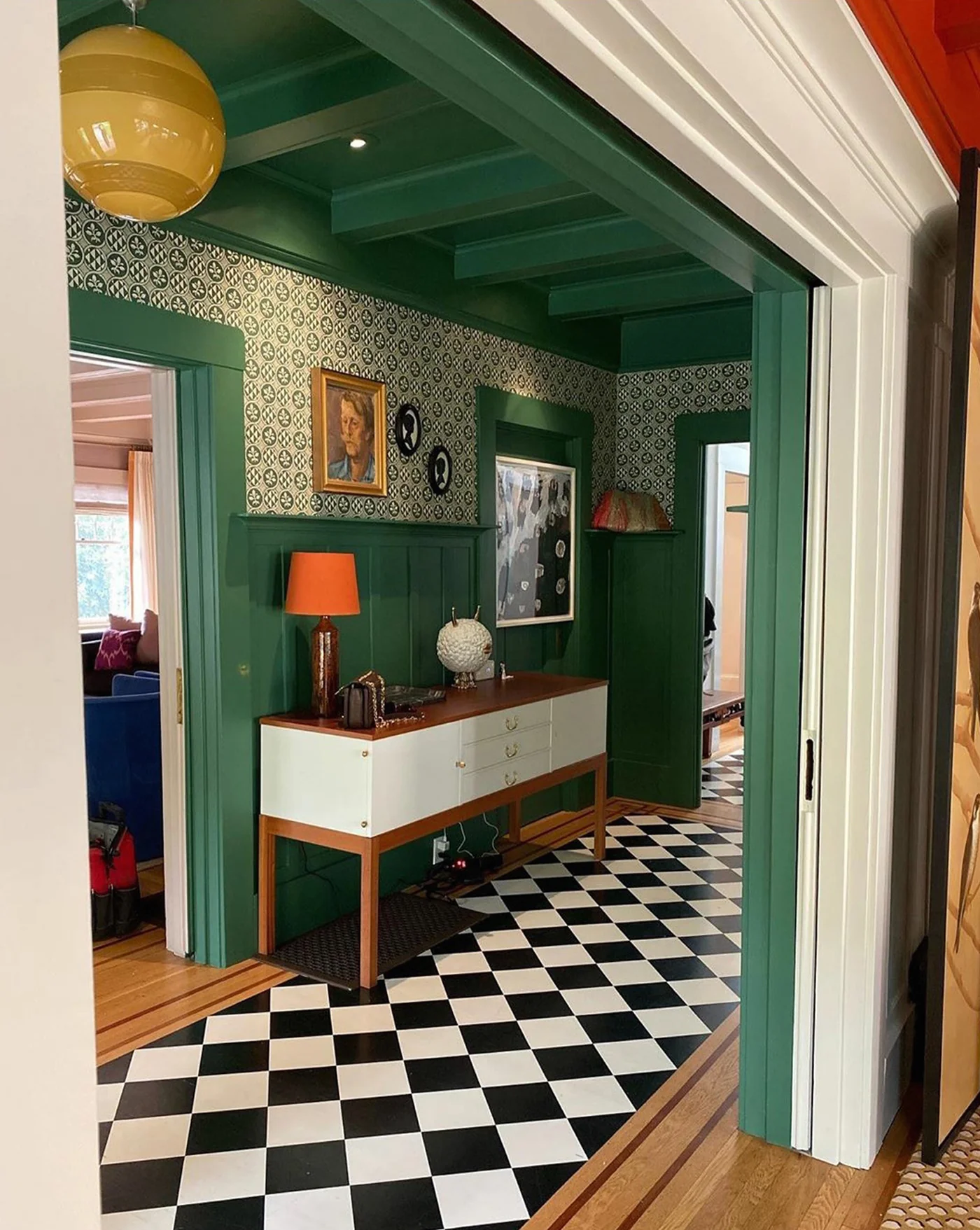 hall avec sol à damier noir et blanc, murs verts et papier-peint graphique vert