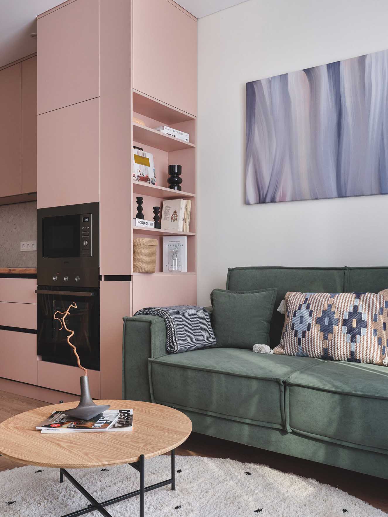 pink kitchen and living room with green sofa in a two-room 42sqm apartment