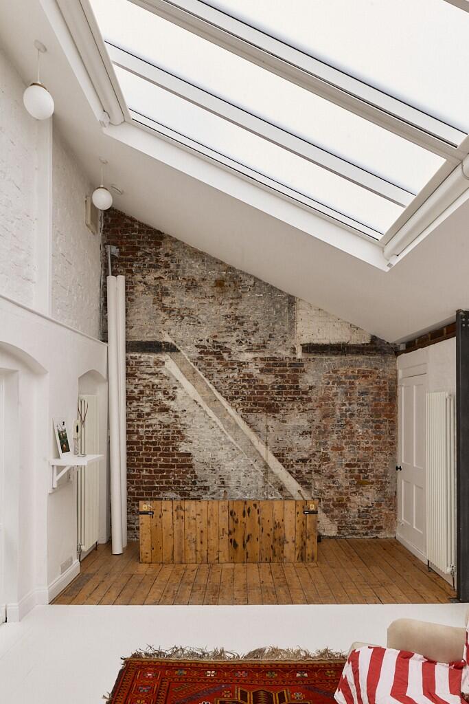 salon murs de briques patinées ancien appartement loft avec verrières du photographe de mode Tim Walker à Londres décoration contemporaine et industrielle 