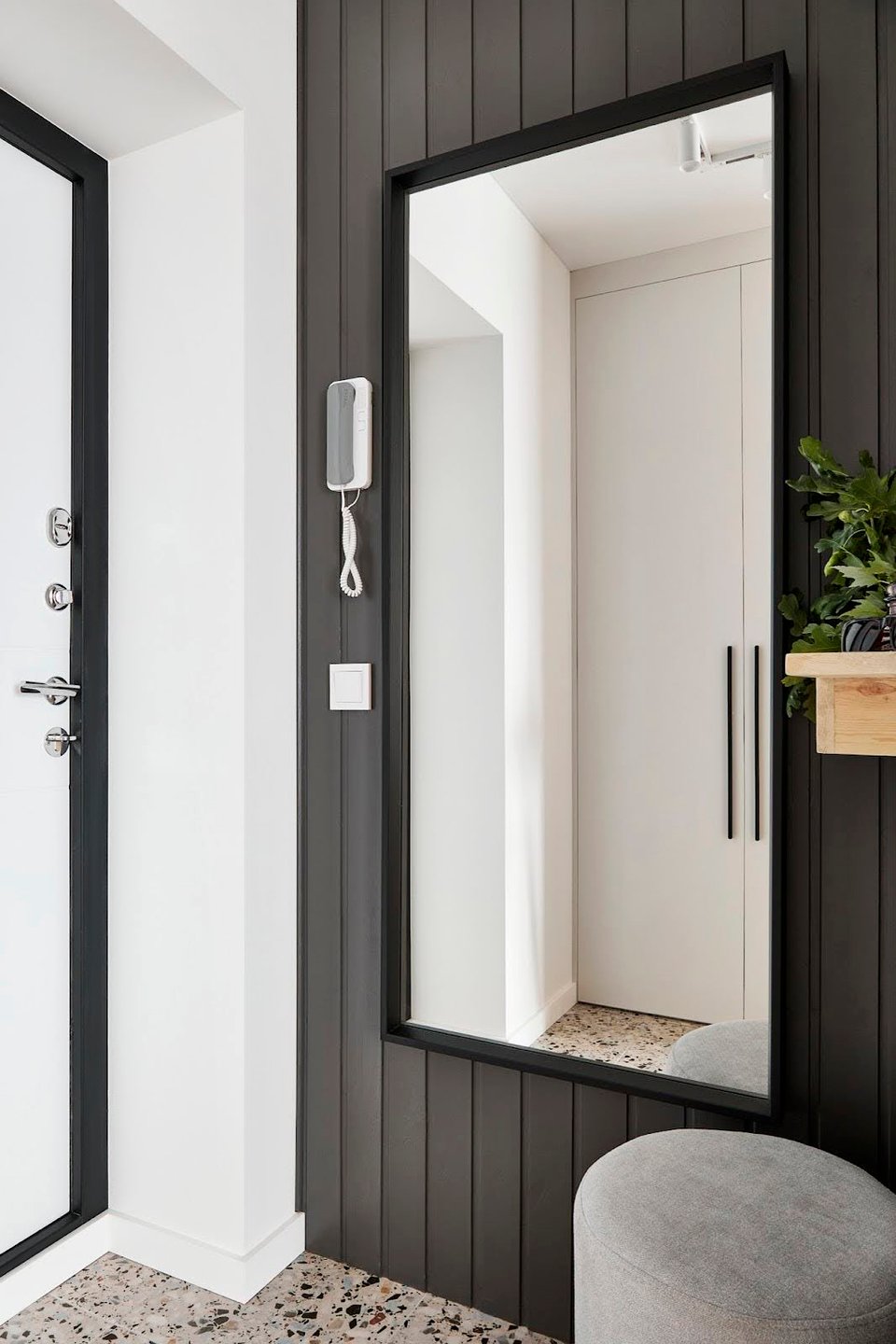 entrée grise avec murs lambrissés miroir et tabouret sol terrazzo