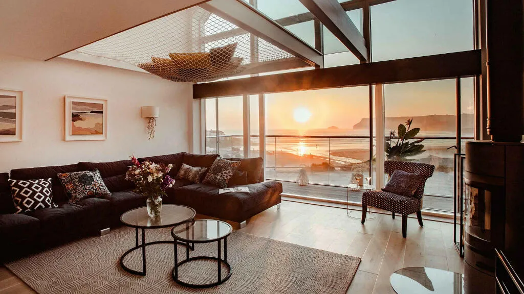 salon design avec baie vitrée vue coucher de soleil