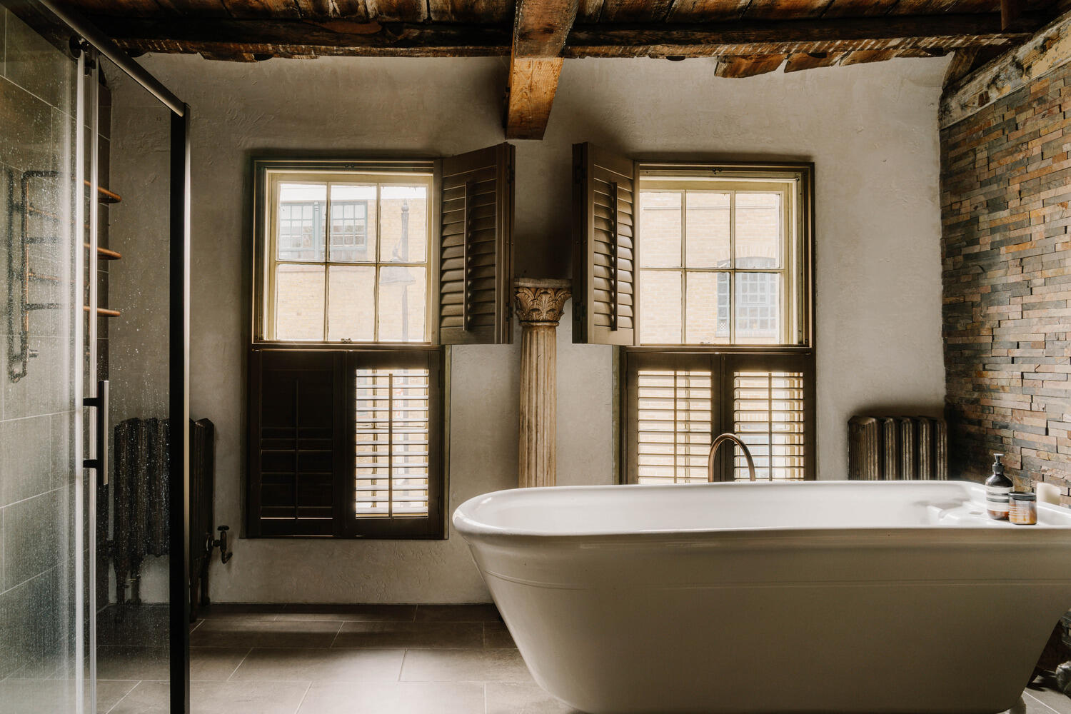 salle de bain rustique et moderne avec poutres et baignoire îlot