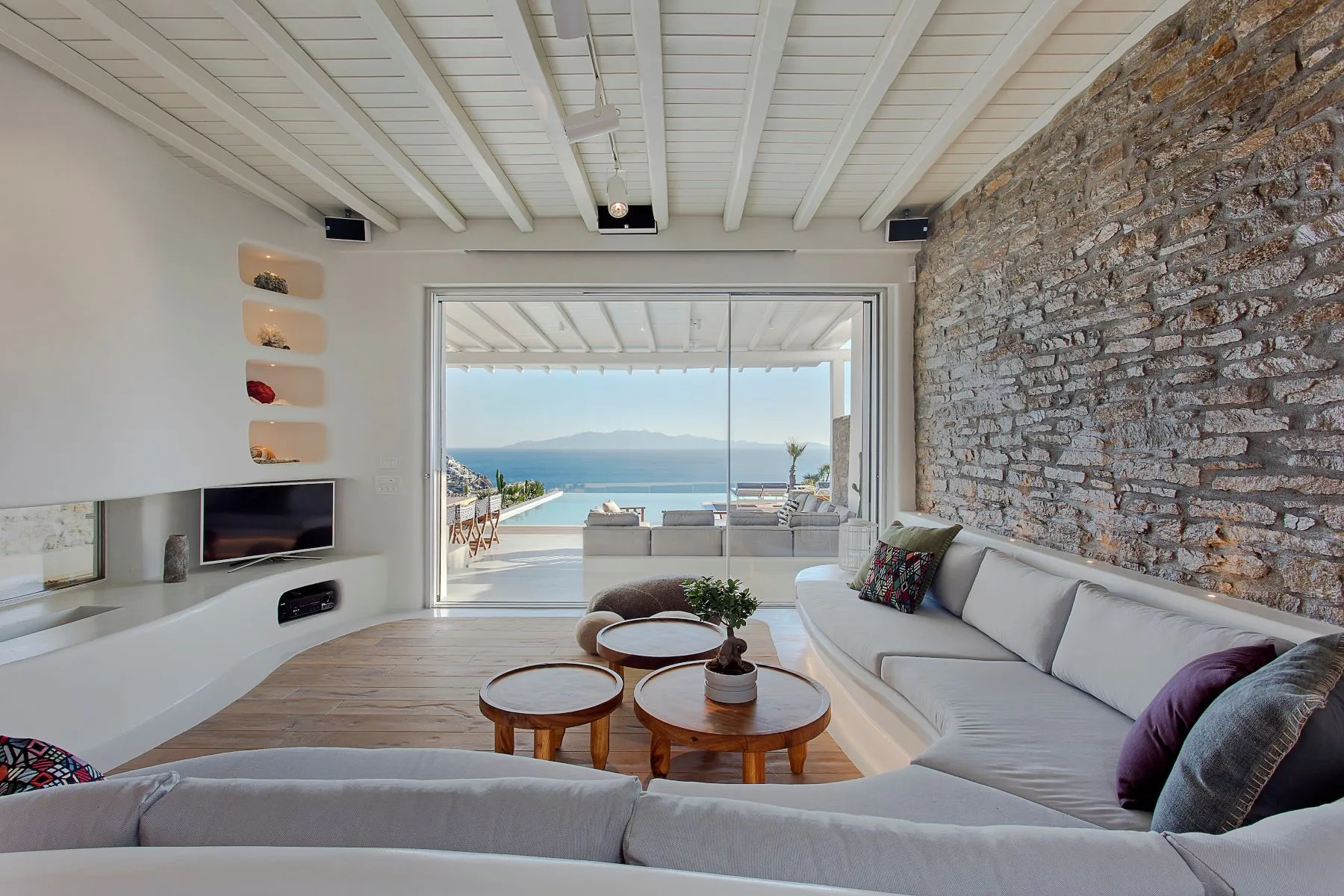 salon vue mer décoration contemporaine mur de pierres et cheminée maison design à Mykonos avec piscine salon vue mer décoration contemporaine mur de pierres et cheminée maison design à Mykonos avec piscine